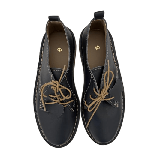 Pair of black leather shoes with tan laces on a white background