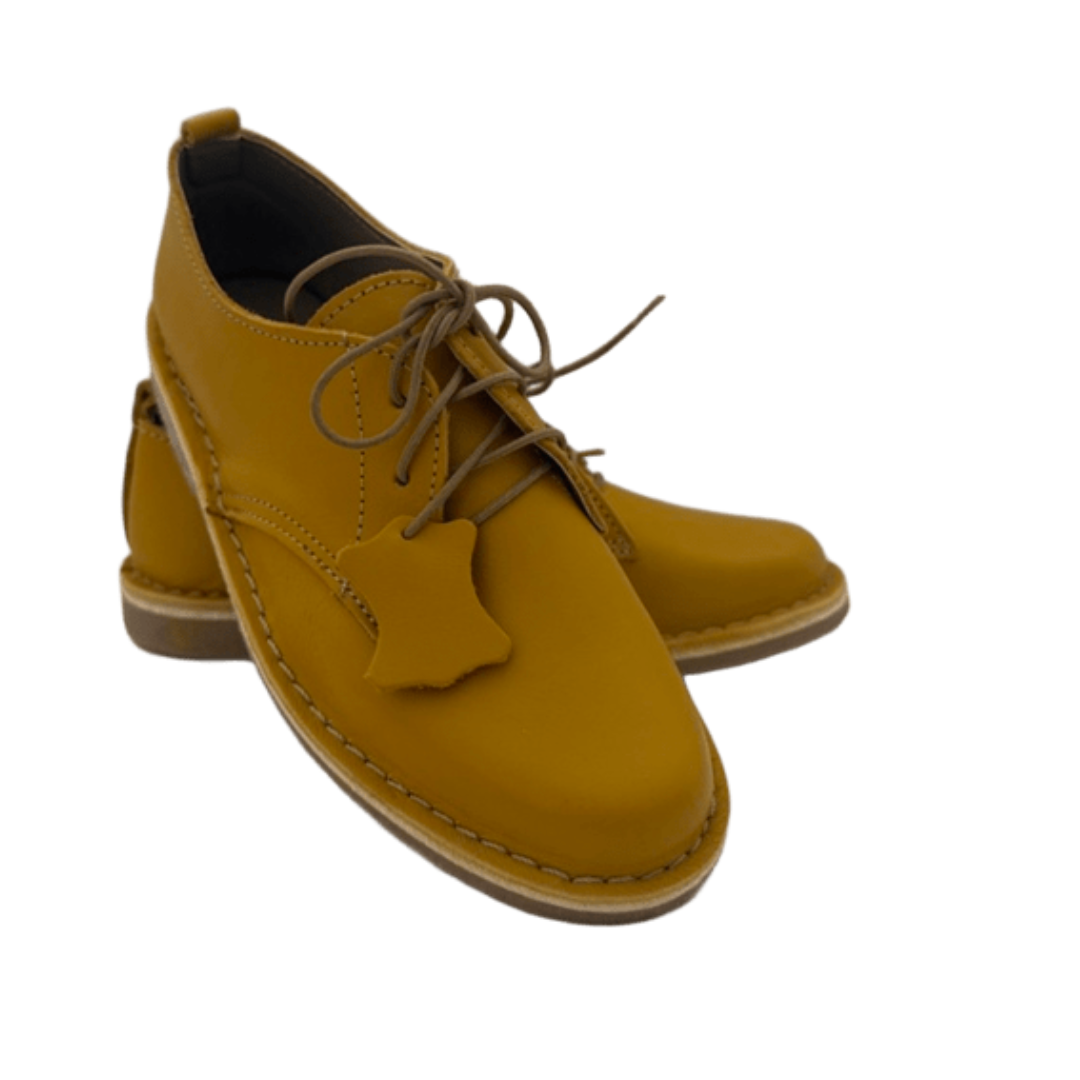 Pair of mustard yellow shoes with brown laces on a white background From the front