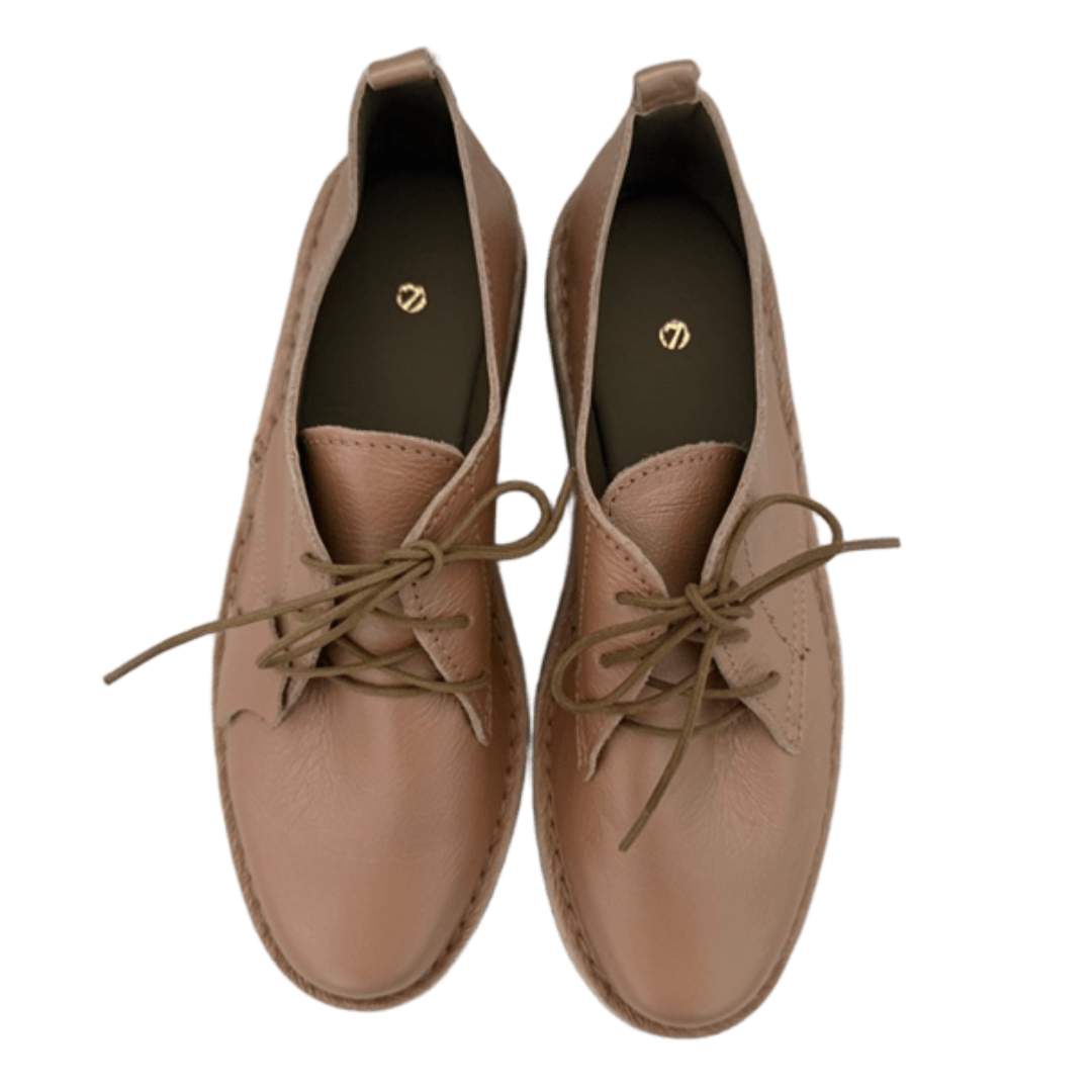 Pair of rose gold leather shoes with laces on a white background From above