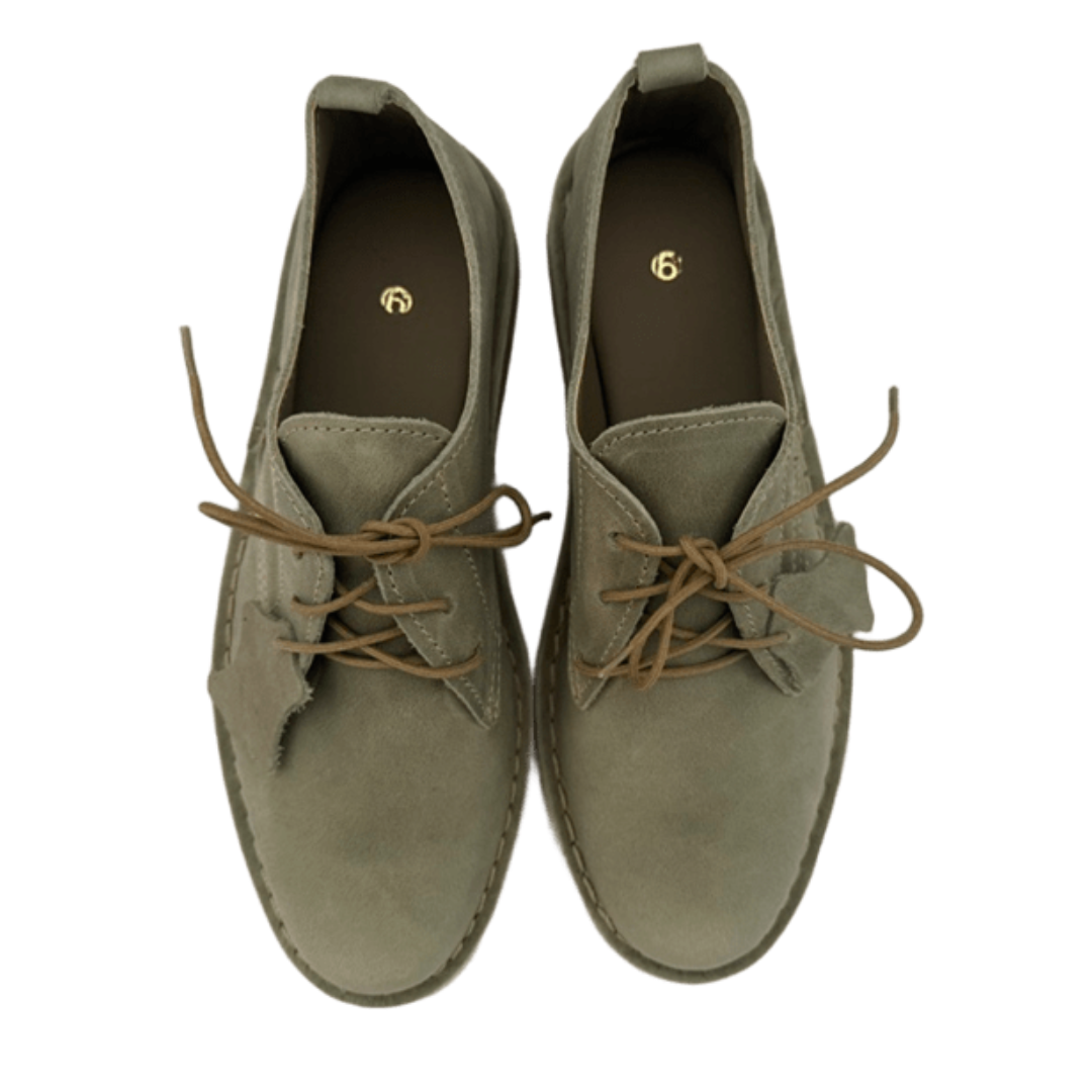Pair of sage green shoes with brown laces on a white background from above