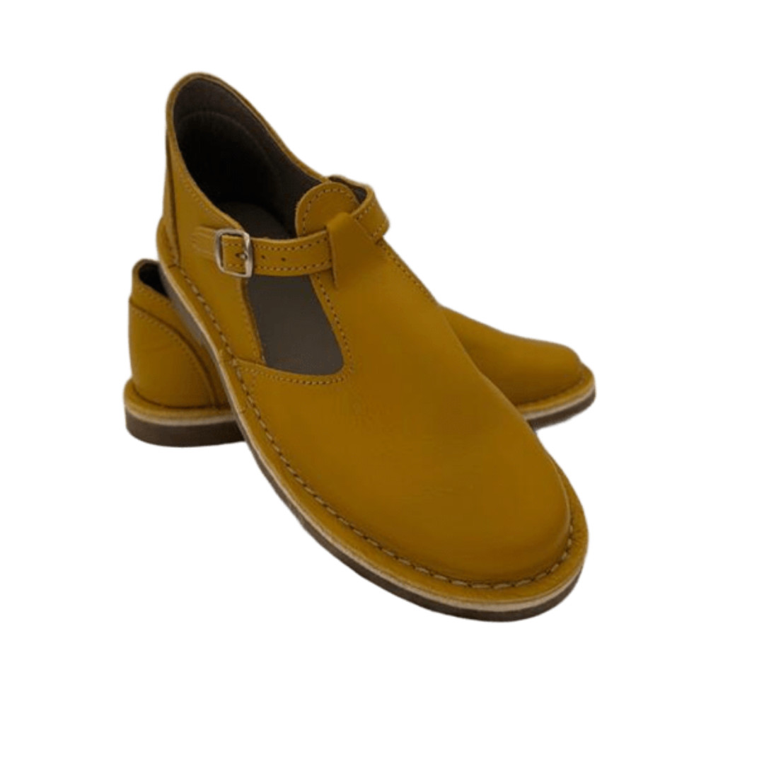 Pair of mustard yellow shoes with a buckle strap on a white background from the front