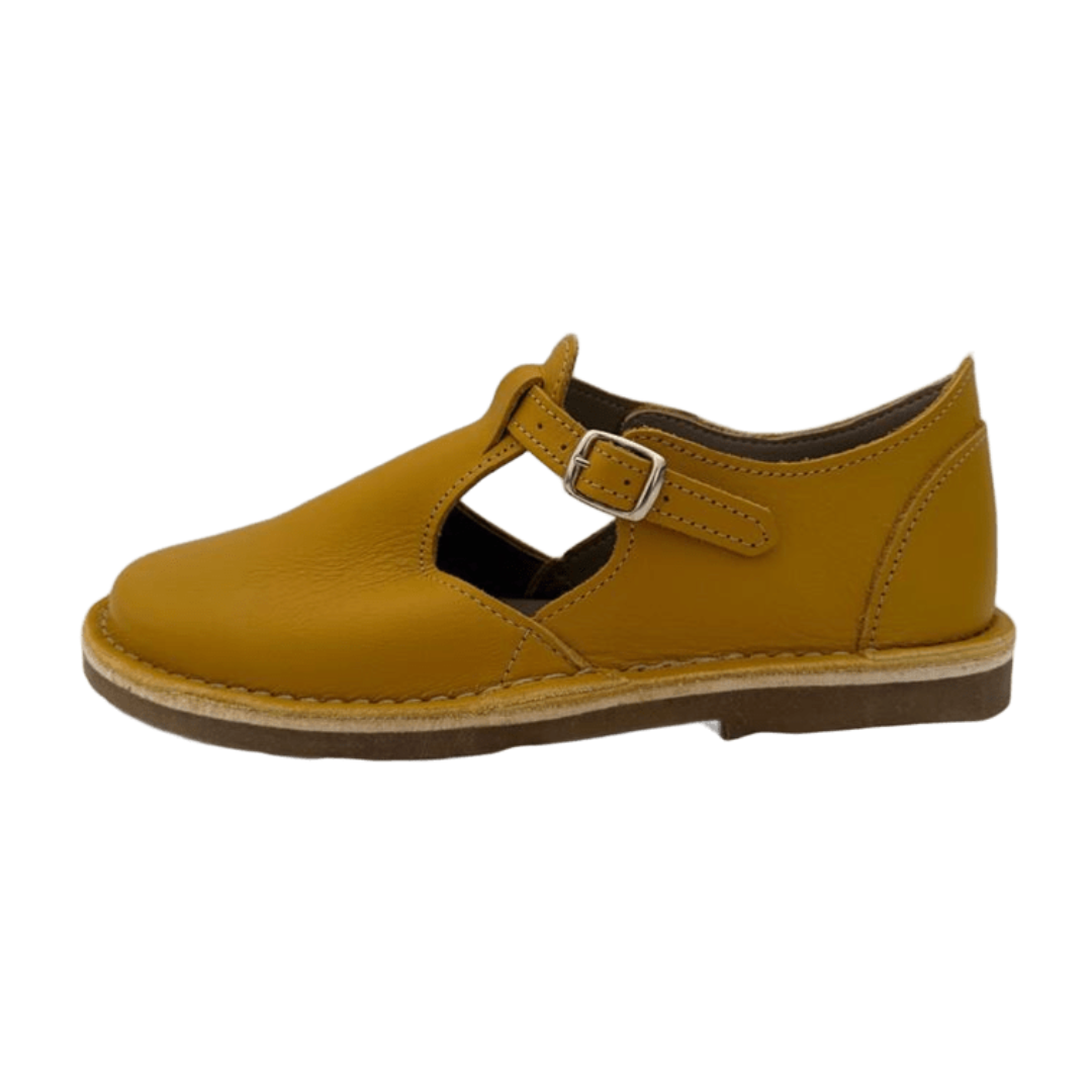 mustard yellow shoe with a buckle strap on a white background from the side