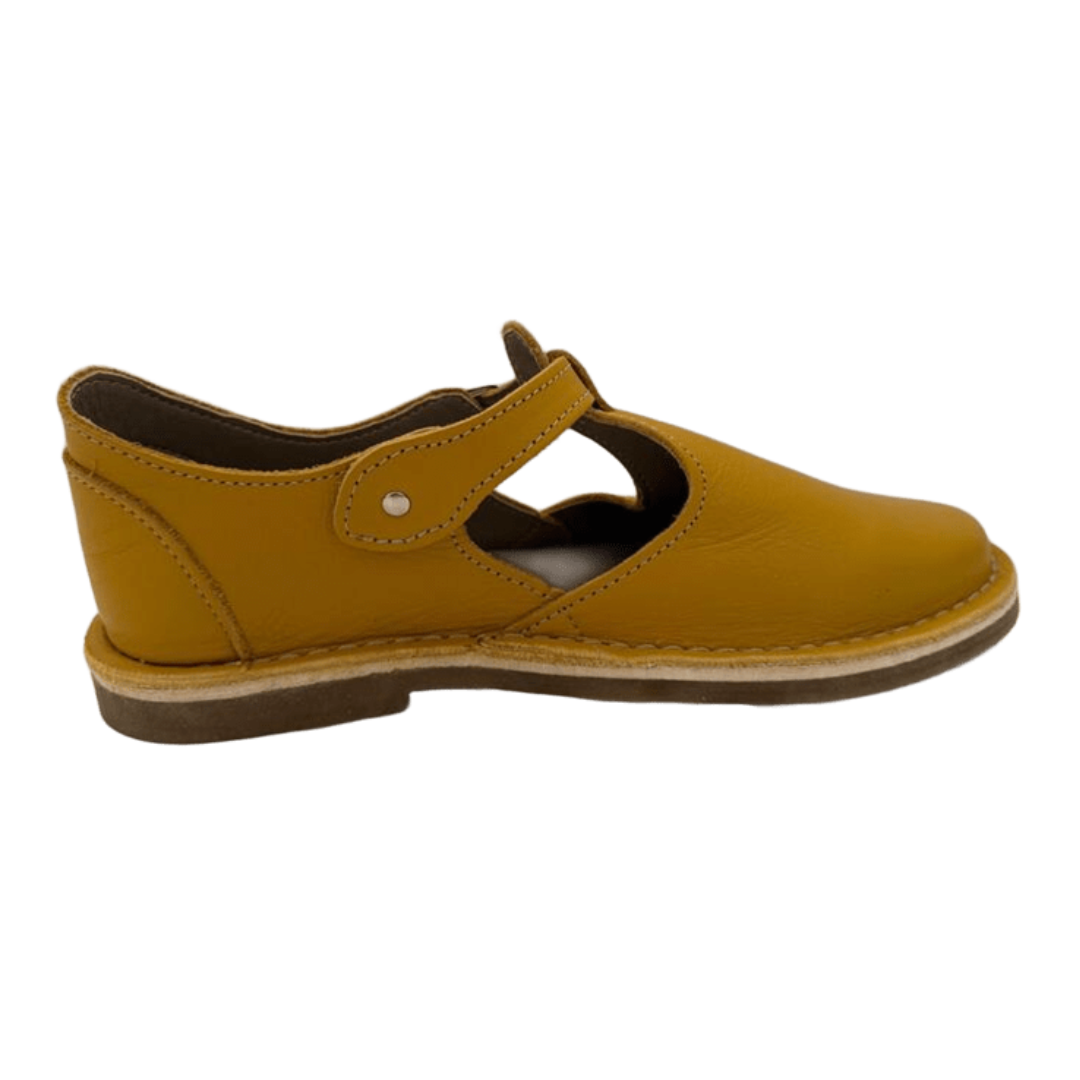 mustard yellow shoe with a buckle strap on a white background from the side